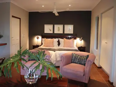 a bedroom with a large bed and a chair at Heuglins Lodge in White River