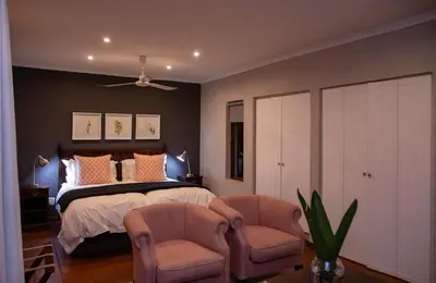 a bedroom with a bed and two chairs at Heuglins Lodge in White River