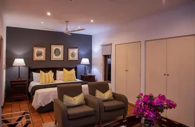 a bedroom with a large bed and two chairs at Heuglins Lodge in White River