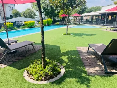 a pool with a picnic table and a tree in a yard at The Luxurious Retreat in Kyalami in Midrand