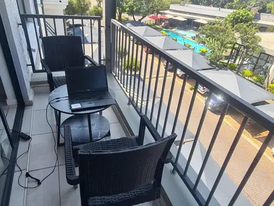 a balcony with two chairs and a laptop on a table at The Luxurious Retreat in Kyalami in Midrand