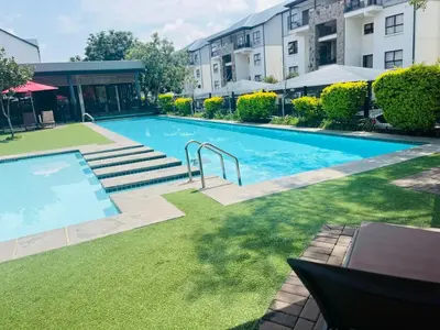 a large swimming pool in a yard with buildings at The Luxurious Retreat in Kyalami in Midrand