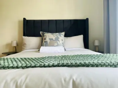 a bed with a green blanket on top of it at The Luxurious Retreat in Kyalami in Midrand