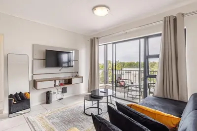 a living room with a couch and a tv at The Luxurious Retreat in Kyalami in Midrand
