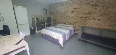 a bedroom with a bed and a couch and a brick wall at 329 on 30th Avenue Villieria Aimee in Pretoria