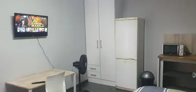 a kitchen with a refrigerator and a tv on the wall at 329 on 30th Avenue Villieria Aimee in Pretoria