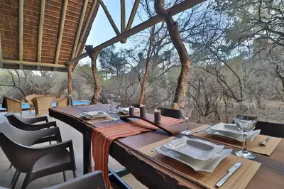 a wooden table with glasses and napkins on top at Lodana -next to Crocodile River in Marloth Park