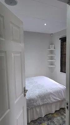 a white bedroom with a bed and a window at ntaleguesthouse in Benoni