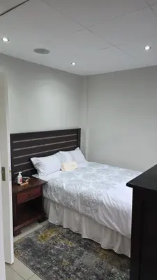 a bedroom with a bed and a wooden night stand at ntaleguesthouse in Benoni