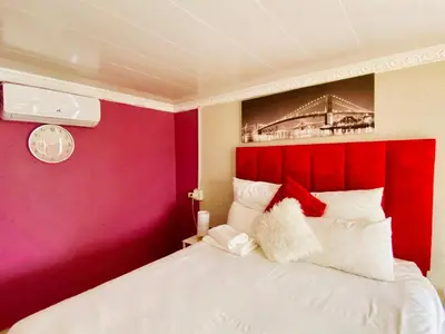 a bedroom with a red wall and a white bed at Pebetse Guesthouse in Acornhoek