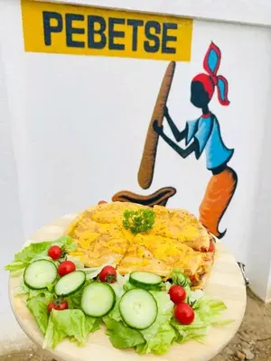 a plate of food with a picture of a woman with a knife at Pebetse Guesthouse in Acornhoek