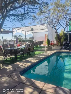 a swimming pool in a yard with chairs and a table at Pebetse Guesthouse in Acornhoek
