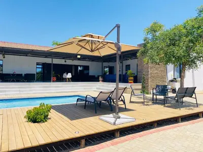 a patio with chairs and an umbrella next to a pool at Pebetse Guesthouse in Acornhoek