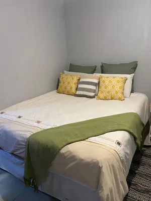 a large bed with yellow and green pillows on it at Royal Retreat Manor in Centurion