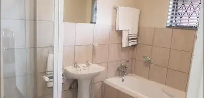 a bathroom with a sink and a toilet and a tub at Peaceful Casa in Kempton Park