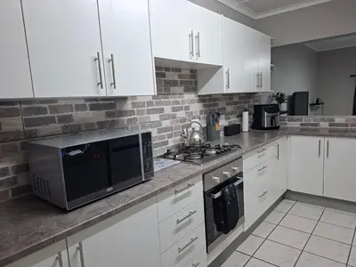 a kitchen with white cabinets and a microwave at Stay-on-Skalie in Nelspruit