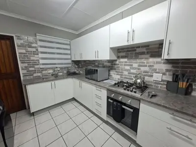 a kitchen with white cabinets and white appliances at Stay-on-Skalie in Nelspruit