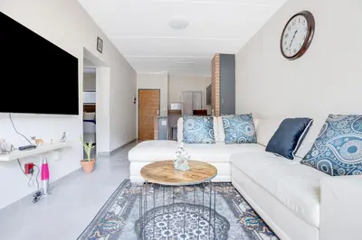 a living room with a white couch and a clock on the wall at Home Away By Waterfall in Midrand