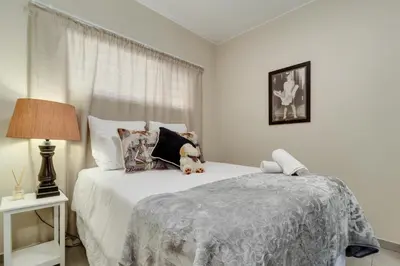 a bedroom with a bed with a teddy bear on it at Home Away By Waterfall in Midrand