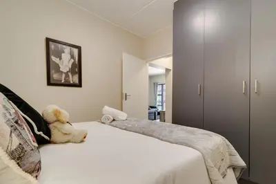 a teddy bear sitting on a bed in a bedroom at Home Away By Waterfall in Midrand