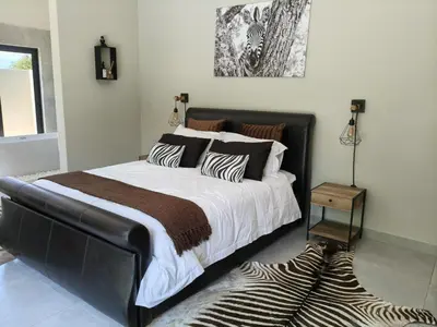 a bedroom with a large bed and a zebra rug at Eagle's Retreat in Marloth Park