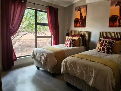 two beds in a room with a window at Eagle's Retreat in Marloth Park