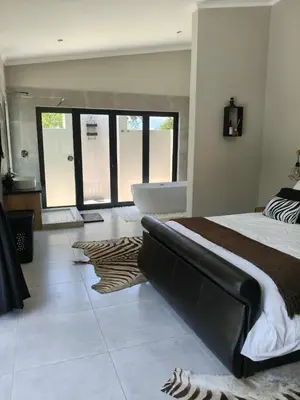 a bedroom with a large bed with a couch in it at Eagle's Retreat in Marloth Park