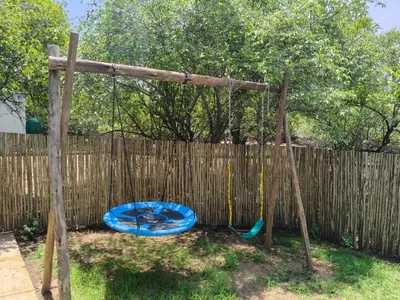 a swing in a backyard with a dog on it at Eagle's Retreat in Marloth Park