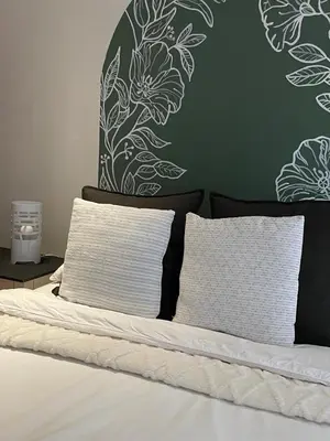a bed with two pillows and a green wall at Oasis Nest in Pretoria