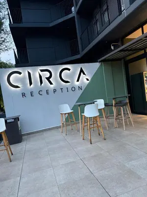 a group of tables and chairs in front of a sign at CIRCA Lynwood Air B&B in Pretoria