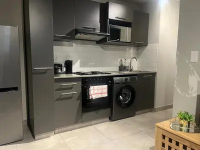 a kitchen with a stove and a washing machine at CIRCA Lynwood Air B&B in Pretoria