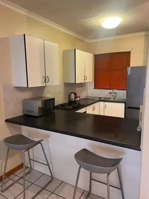 a kitchen with a black counter and two stools at Menlyn Place 506 in Pretoria