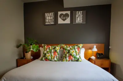 a bedroom with a bed with a white bedspread and some pictures at Villa San Giovanni Accommodation in Pretoria