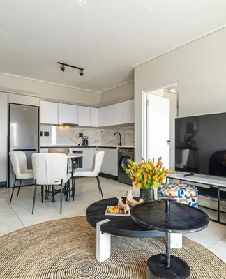 a living room with a table and a kitchen at The Blyde Crystal Lagoon Pretoria in Pretoria