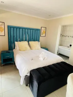 a large bed with a blue headboard in a bedroom at Lethabo Guesthouse
