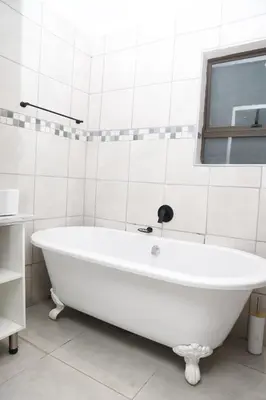 a white bath tub in a bathroom with a window at Lethabo Guesthouse