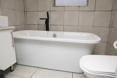 a white bath tub in a bathroom with a toilet at Lethabo Guesthouse