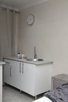 a kitchen with a sink and a clock on the wall at Lethabo Guesthouse