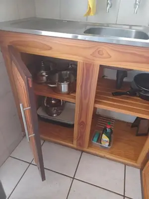 a kitchen sink in a wooden cabinet with pots and pans at The Roaches in White River