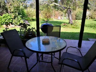 a table and chairs on a patio with a grill at Cottage Suikerbekkie in Dullstroom