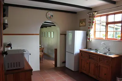a kitchen with a white refrigerator and a table at Cottage Suikerbekkie in Dullstroom