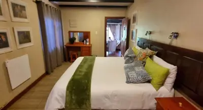 a bedroom with a large bed with colorful pillows at Cottage Suikerbekkie in Dullstroom