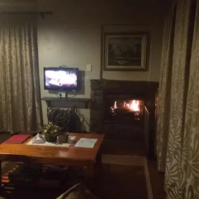 a living room with a television and a fireplace at Cottage Suikerbekkie in Dullstroom