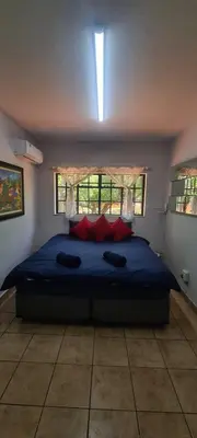 a bedroom with a large blue bed with red pillows at Jireh in Pretoria