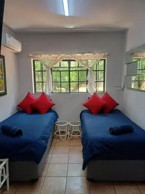 two beds in a room with blue and red pillows at Jireh in Pretoria