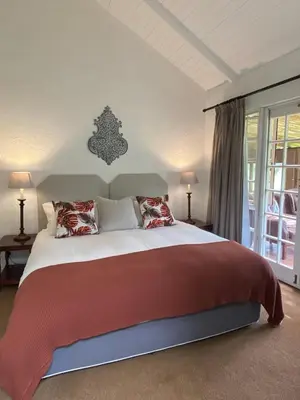 a bedroom with a large bed with red blankets and pillows at Willow Weir River Cottage in Dullstroom