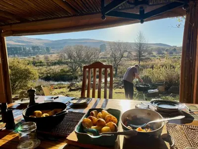 a table with food on it with a man in the background at Willow Weir River Cottage in Dullstroom