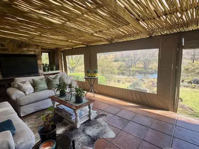 a living room with a couch and a table at Willow Weir River Cottage in Dullstroom