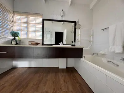 a bathroom with a mirror and a tub and a sink at Willow Weir River Cottage in Dullstroom