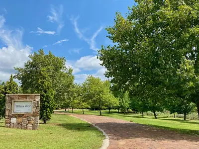 a sign in a park with trees and a path at Willow Weir River Cottage in Dullstroom